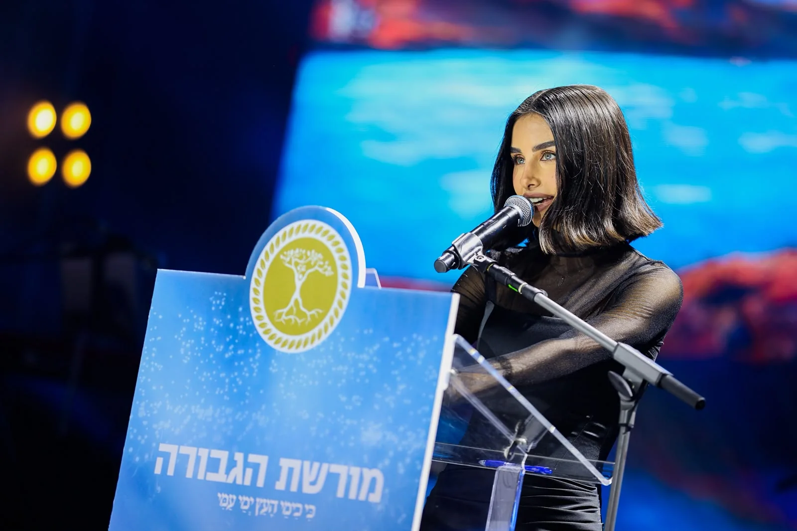Maggie Tabibi at a lectern bearing the Israel Prize emblem